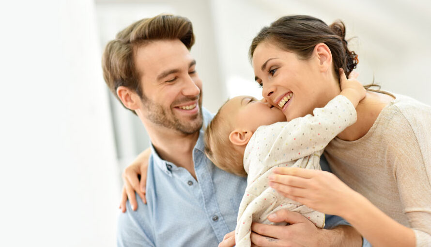 Deux parents prenant leur bébé dans les bras.